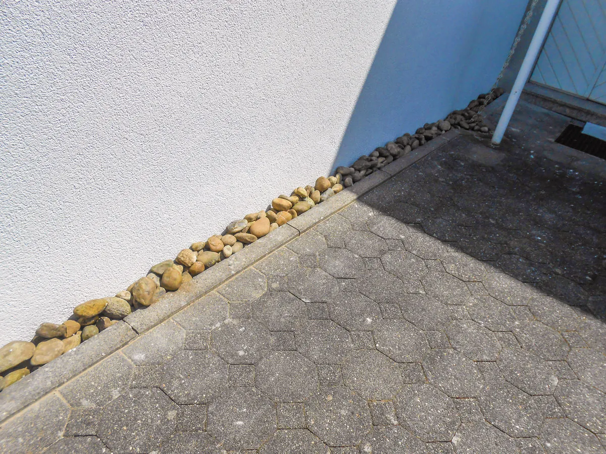 Außenwand mit Feuchteschaden am Sockel und Kiesstreifen