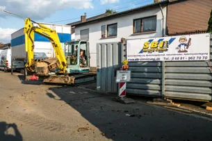 Bagger und Firmenfahrzeug der SBI GmbH an einer Baustelle